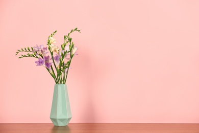 Photo of Beautiful fragrant freesia flowers in vase and space for text on color background