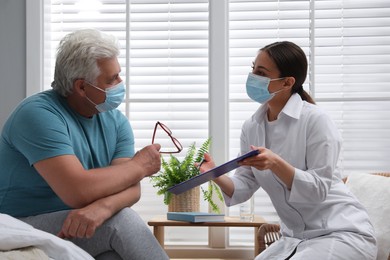 Doctor working with senior man in protective mask at nursing home