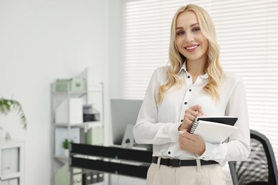 Photo of Happy secretary with notebook in office, space for text