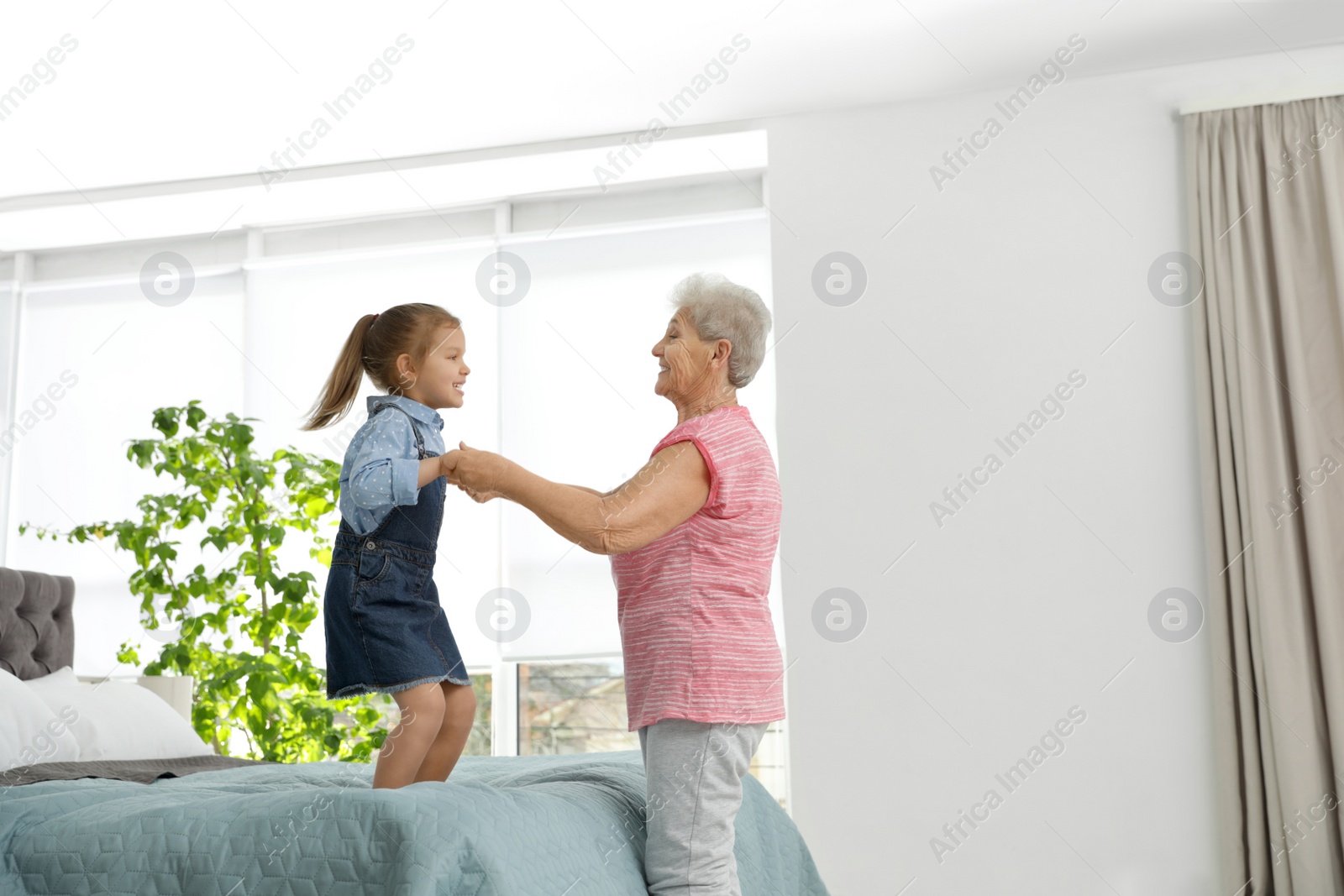 Photo of Cute girl and her grandmother playing together at home