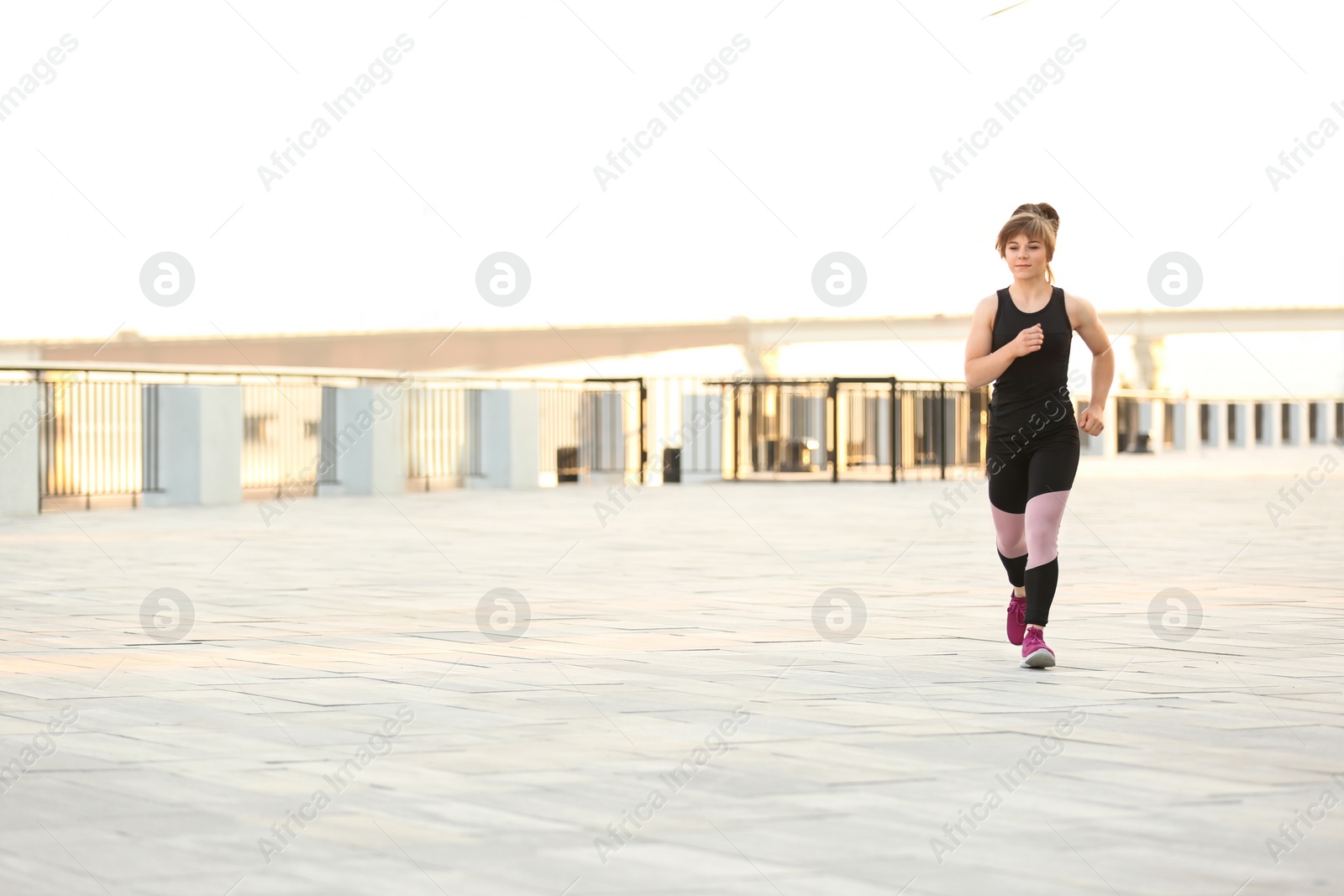 Photo of Young woman running outdoors on sunny day
