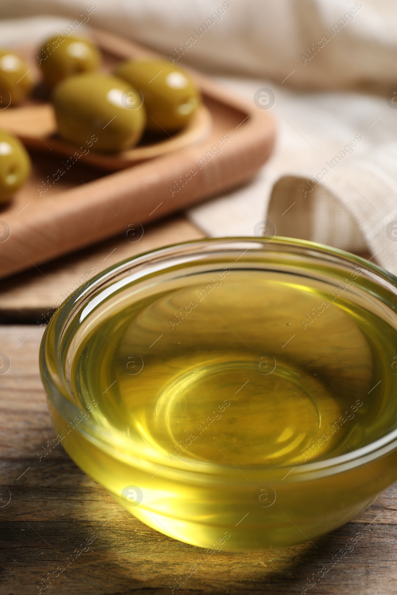 Photo of Bowl of olive oil on wooden table, closeup. Healthy cooking