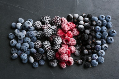 Mix of different frozen berries on black table, flat lay