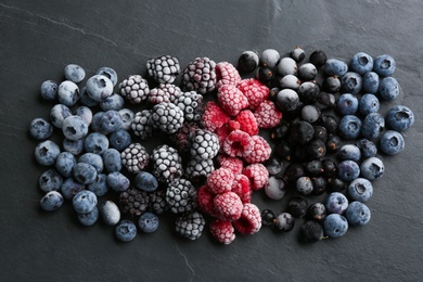 Photo of Mix of different frozen berries on black table, flat lay