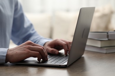 E-learning. Man using laptop during online lesson at table indoors, closeup