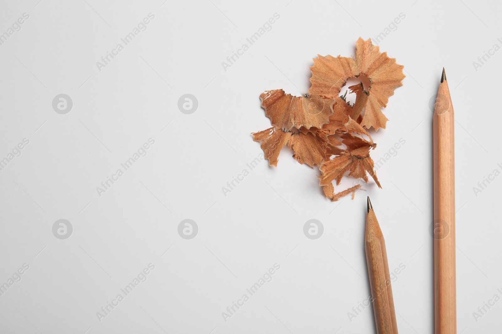 Photo of Sharp graphite pencils and shavings on white background, top view. Space for text