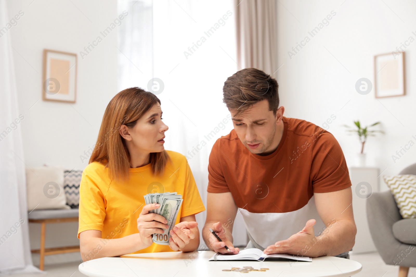 Photo of Sad couple counting money in living room