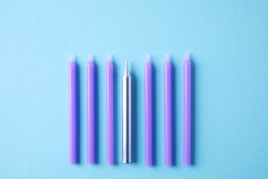 Bright birthday candles on light blue background, flat lay