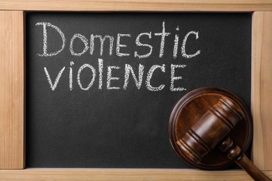 Photo of Words DOMESTIC VIOLENCE and gavel on blackboard, flat lay