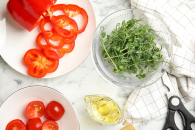 Fresh microgreen for tasty salad on white marble table, flat lay