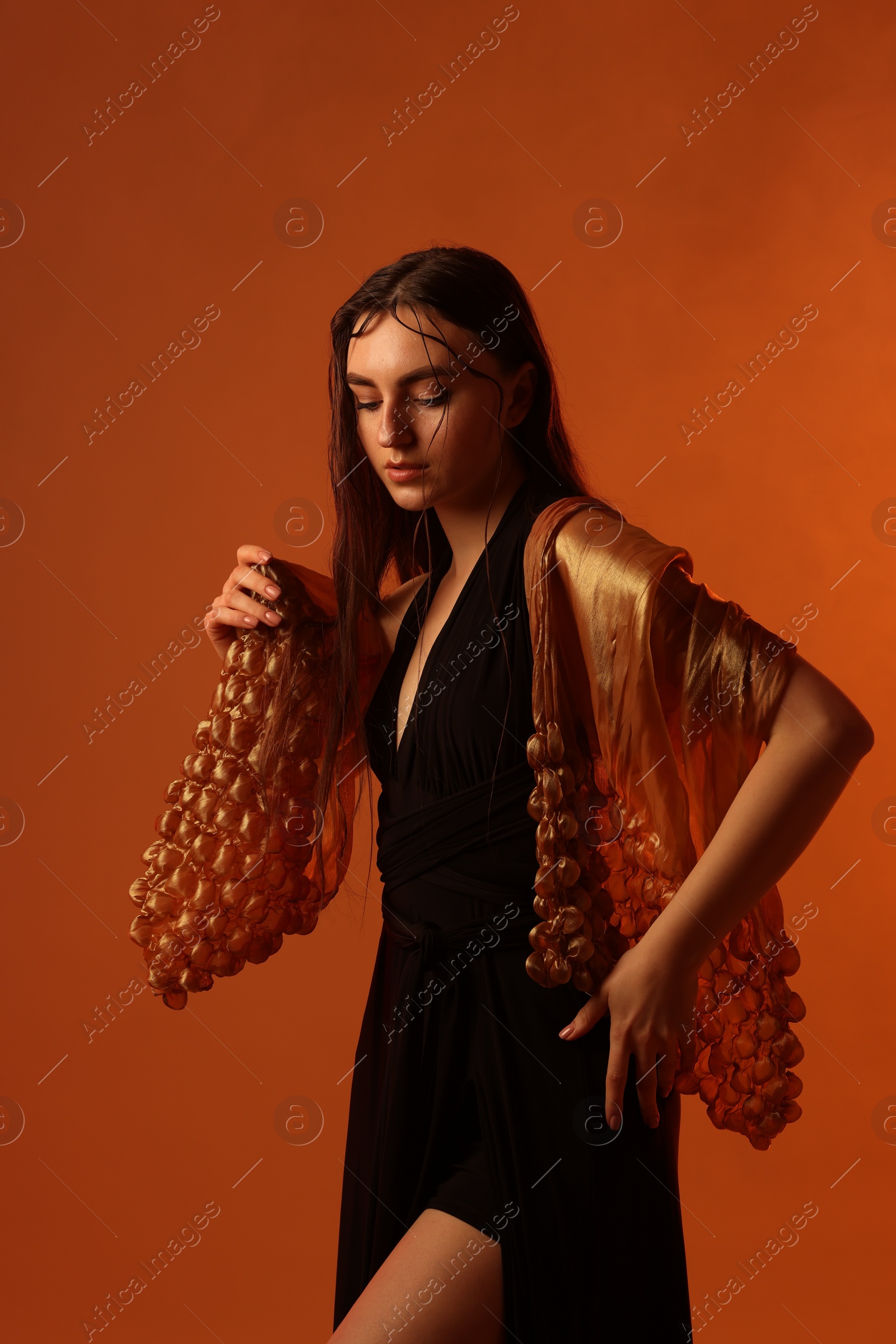 Photo of Beautiful woman in black dress and shawl posing on brown background