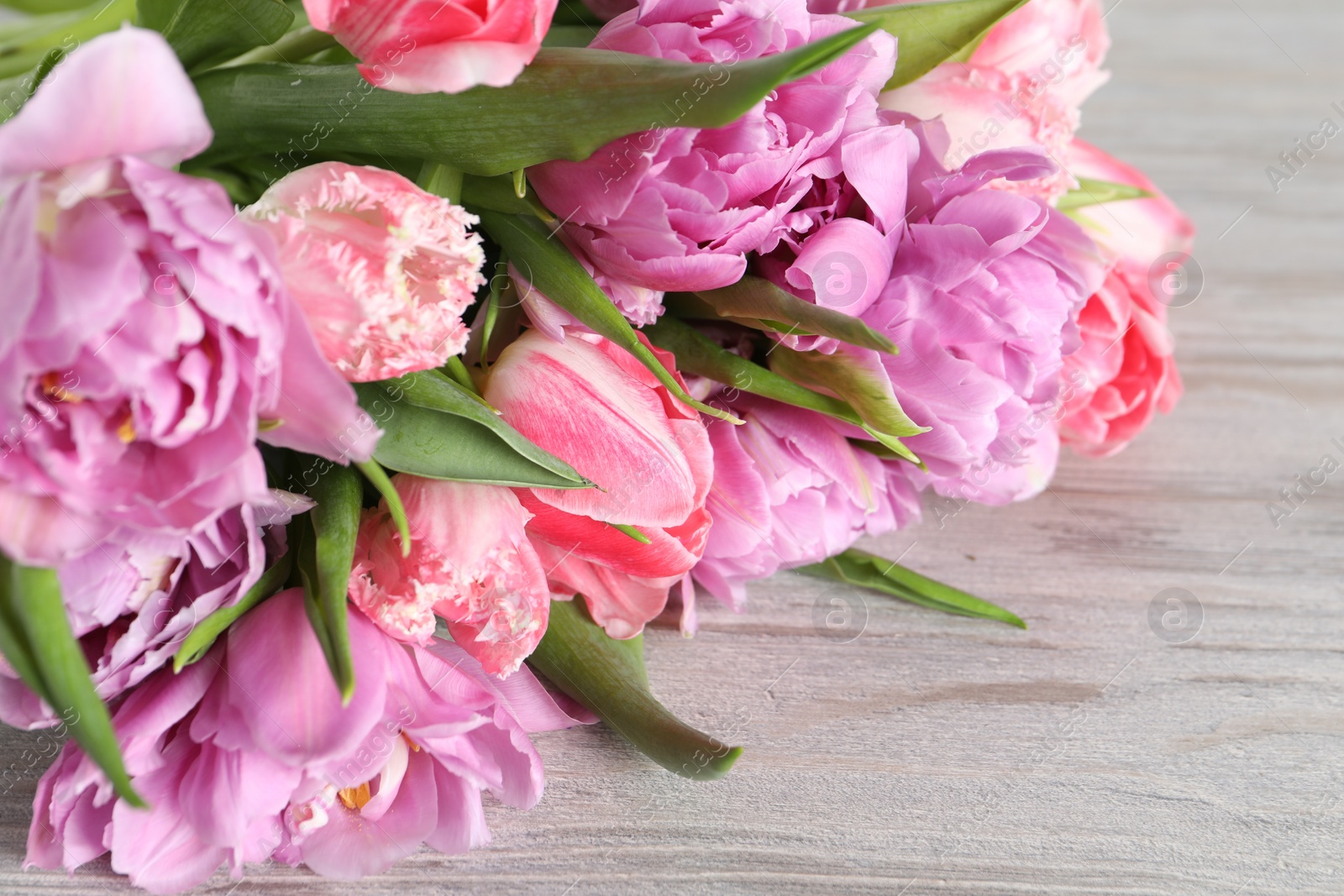 Photo of Beautiful bouquet of colorful tulip flowers on wooden table, closeup