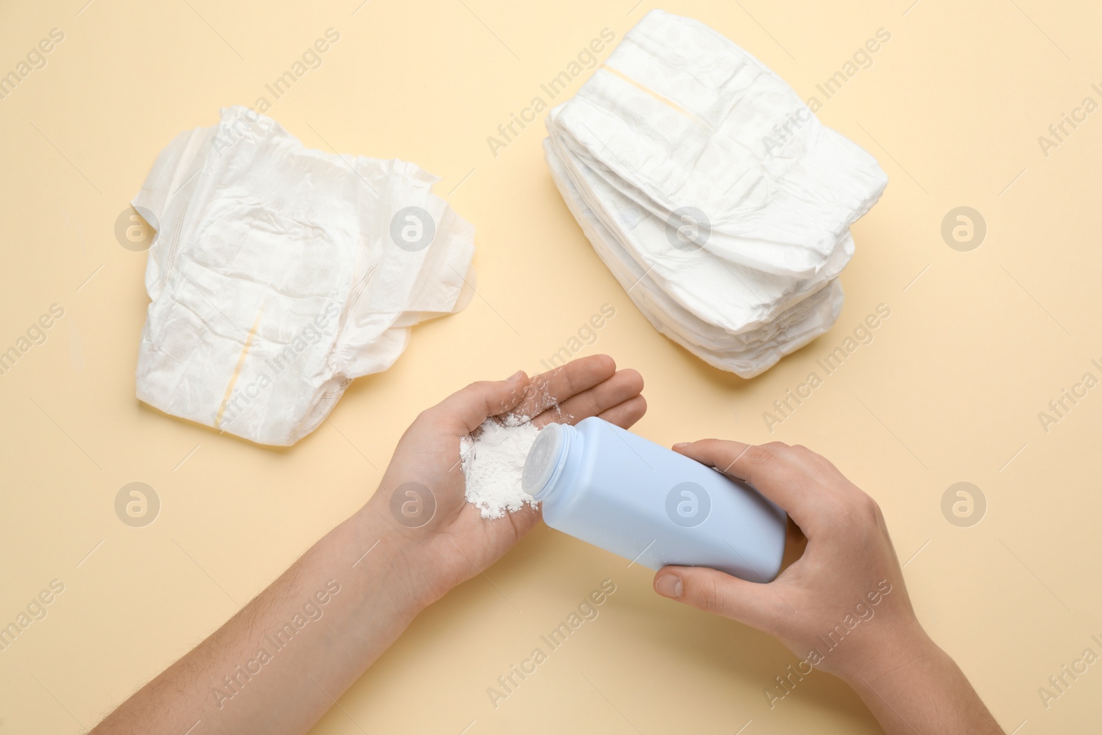 Photo of Woman applying dusting powder on beige background, top view