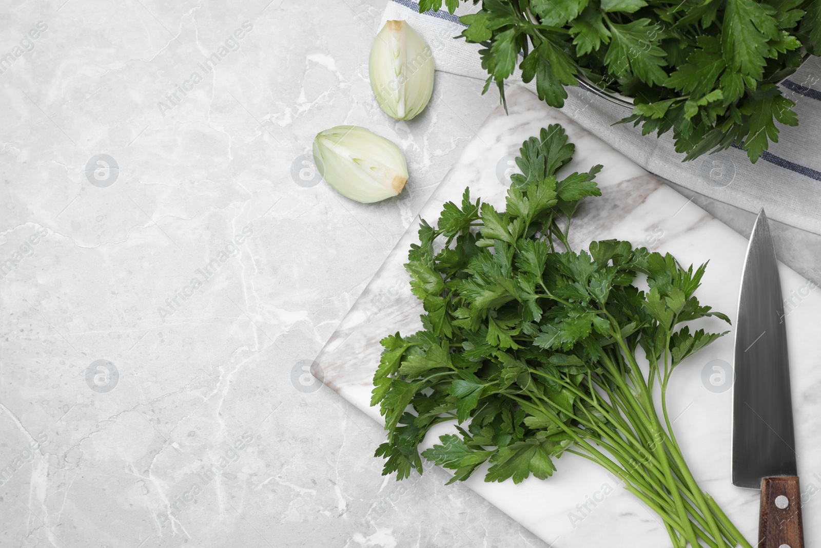 Photo of Marble board with fresh green parsley and knife on grey table, flat lay. Space for text