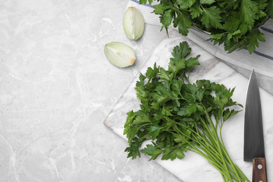 Marble board with fresh green parsley and knife on grey table, flat lay. Space for text