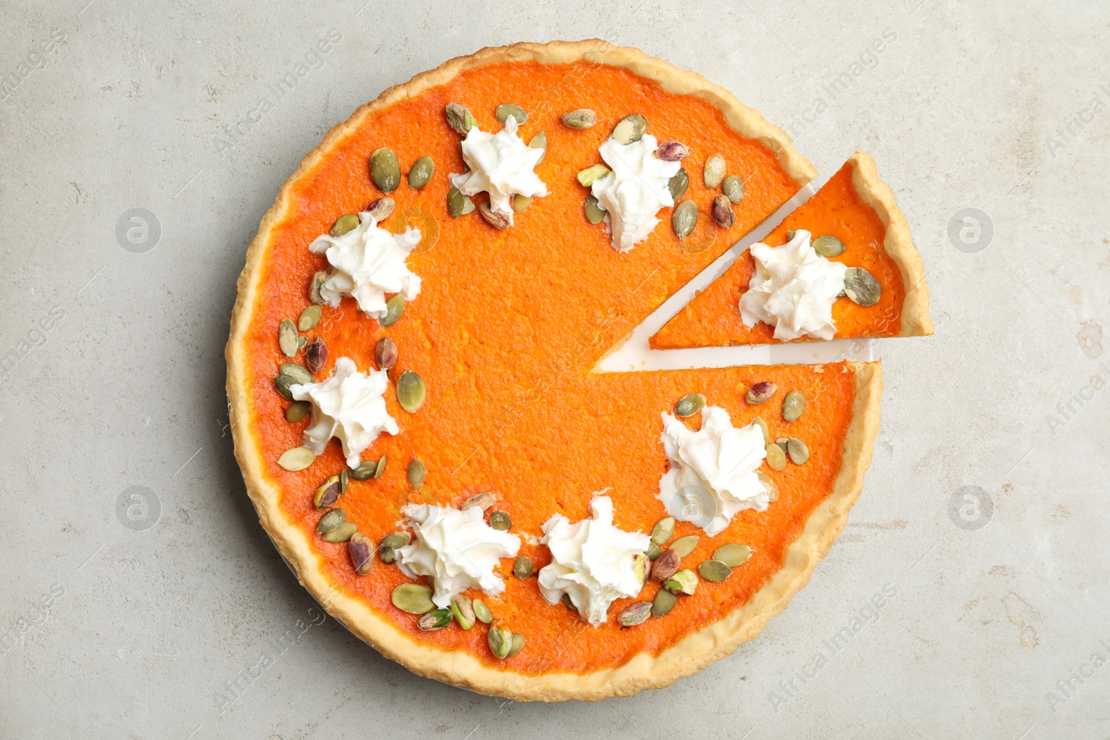 Photo of Delicious homemade pumpkin pie on light table, top view