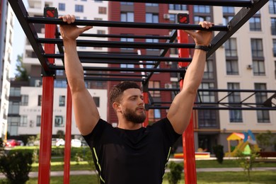 Photo of Man training on monkey bars at outdoor gym