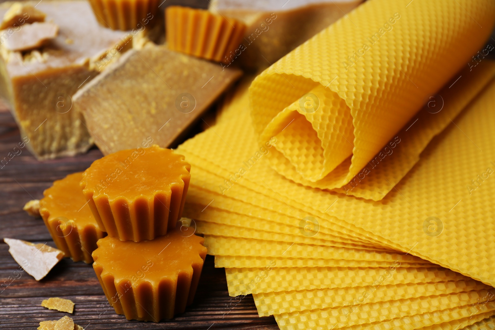 Photo of Different natural beeswax blocks and sheets on wooden table, closeup