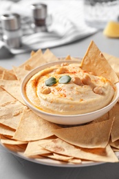 Photo of Delicious creamy hummus served with chips on table, closeup