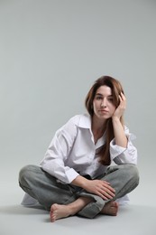 Photo of Beautiful young woman sitting on grey background