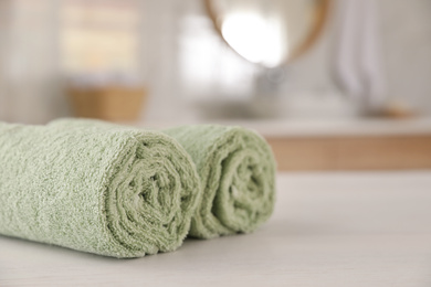 Photo of Clean rolled towels on white wooden table in bathroom. Space for text