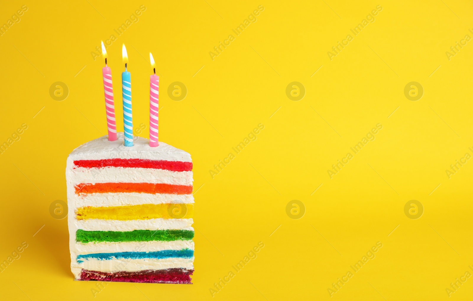 Photo of Slice of delicious rainbow cake with candles on color background