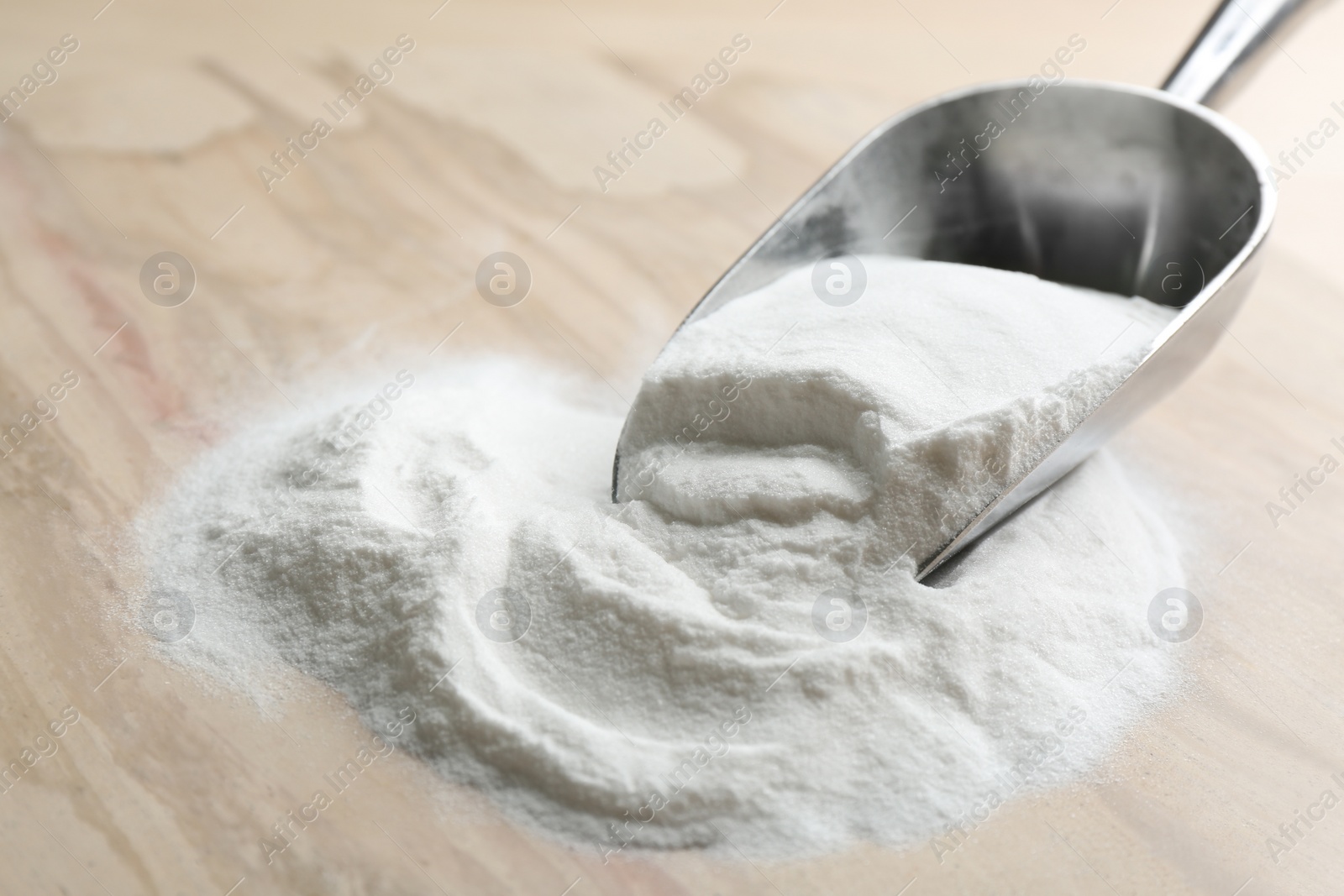 Photo of Baking soda in scoop on wooden table