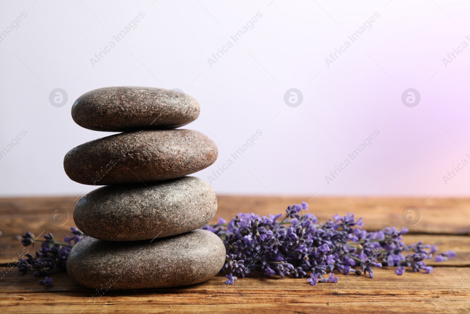 Photo of Lavender flowers and spa stones on wooden table. Space for text