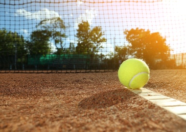 Photo of Bright yellow tennis ball on clay court. Space for text