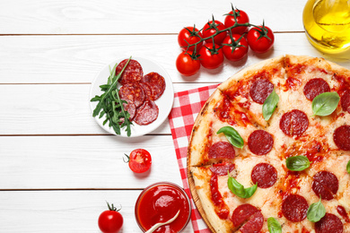 Flat lay composition with hot pepperoni pizza on white wooden table