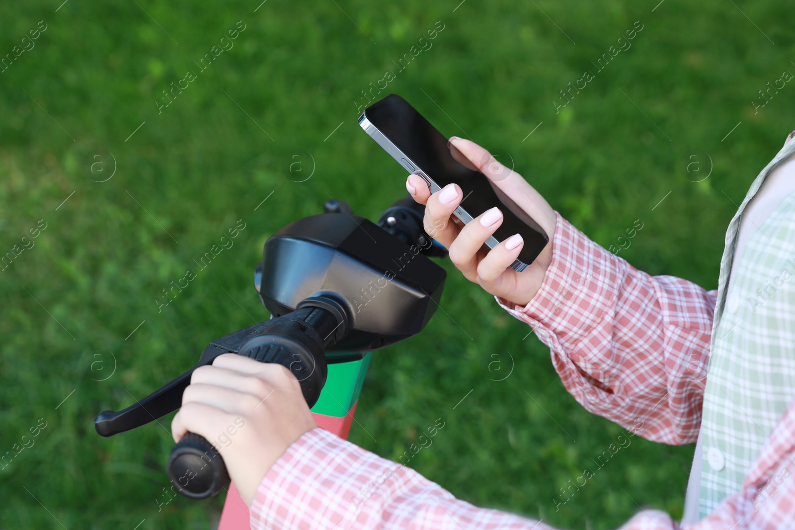 Photo of Woman using smartphone to pay and unblock electric kick scooter outdoors, closeup