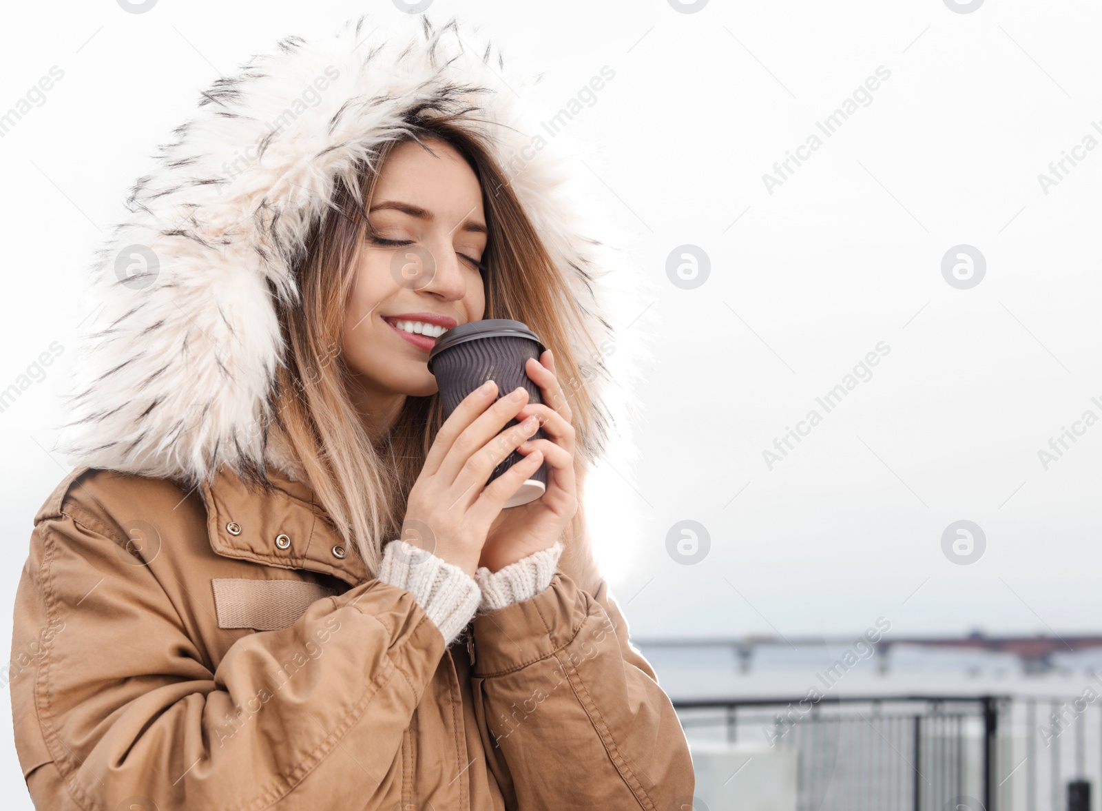 Photo of Young woman with cup of coffee walking outdoors. Space for text