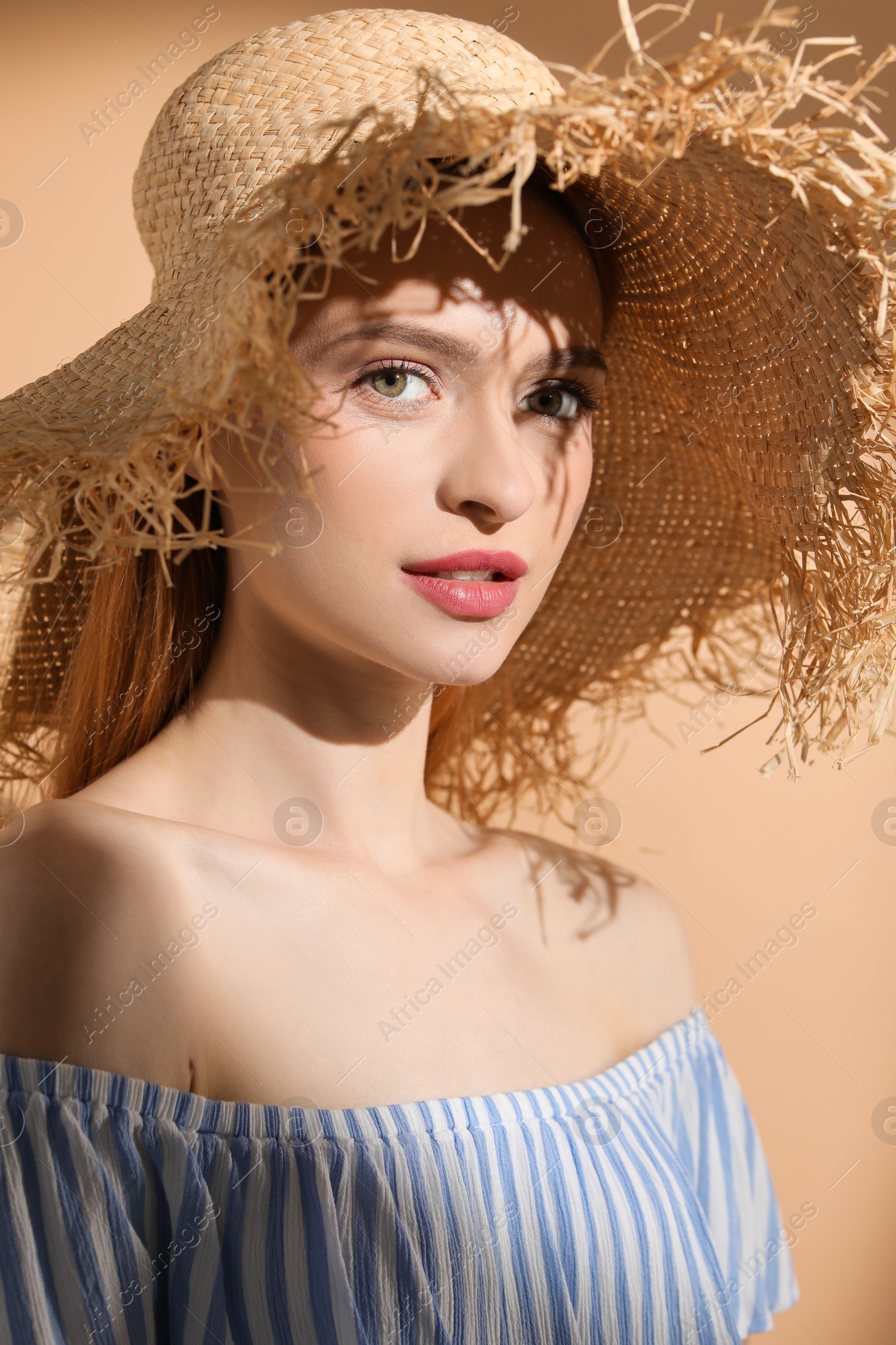 Photo of Beautiful young woman in sunlight on beige background