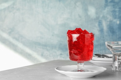 Photo of Red jelly in glass on table against color background. Space for text