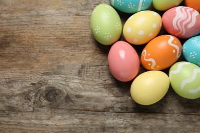 Many colorful painted Easter eggs on wooden background, top view. Space for text