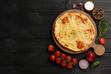 Delicious khachapuri with cheese, vegetables and spices on dark wooden table, flat lay. Space for text