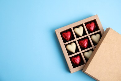 Photo of Tasty heart shaped chocolate candies on light blue background, flat lay with space for text. Happy Valentine's day