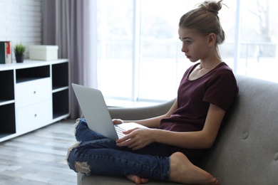 Shocked teenage girl with laptop in room. Danger of internet