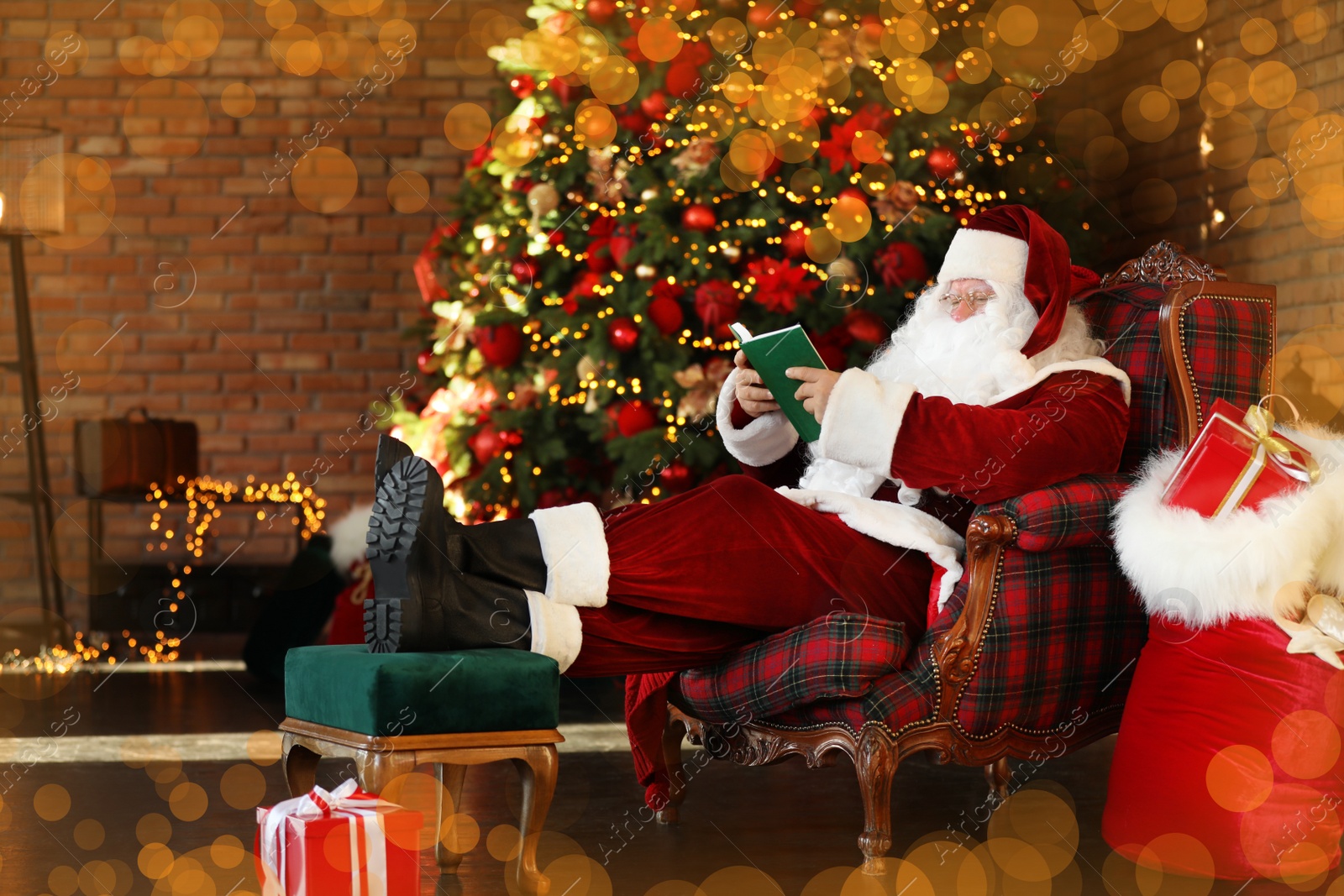 Photo of Santa Claus reading book near decorated Christmas tree indoors