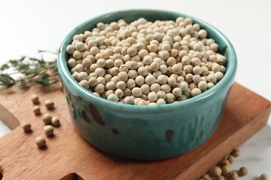 Aromatic spice. White pepper in bowl on white table, closeup