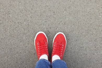 Woman in stylish gumshoes on asphalt, top view