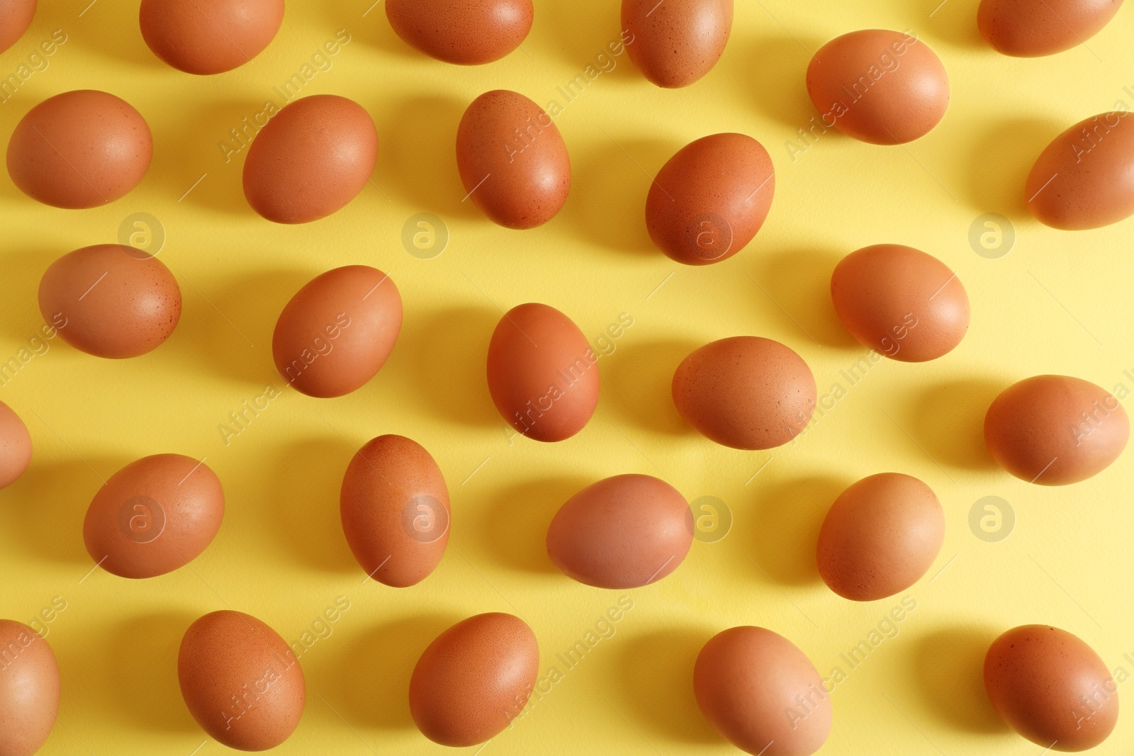 Photo of Fresh chicken eggs on yellow background, flat lay