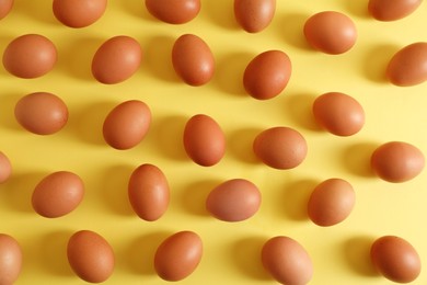 Fresh chicken eggs on yellow background, flat lay