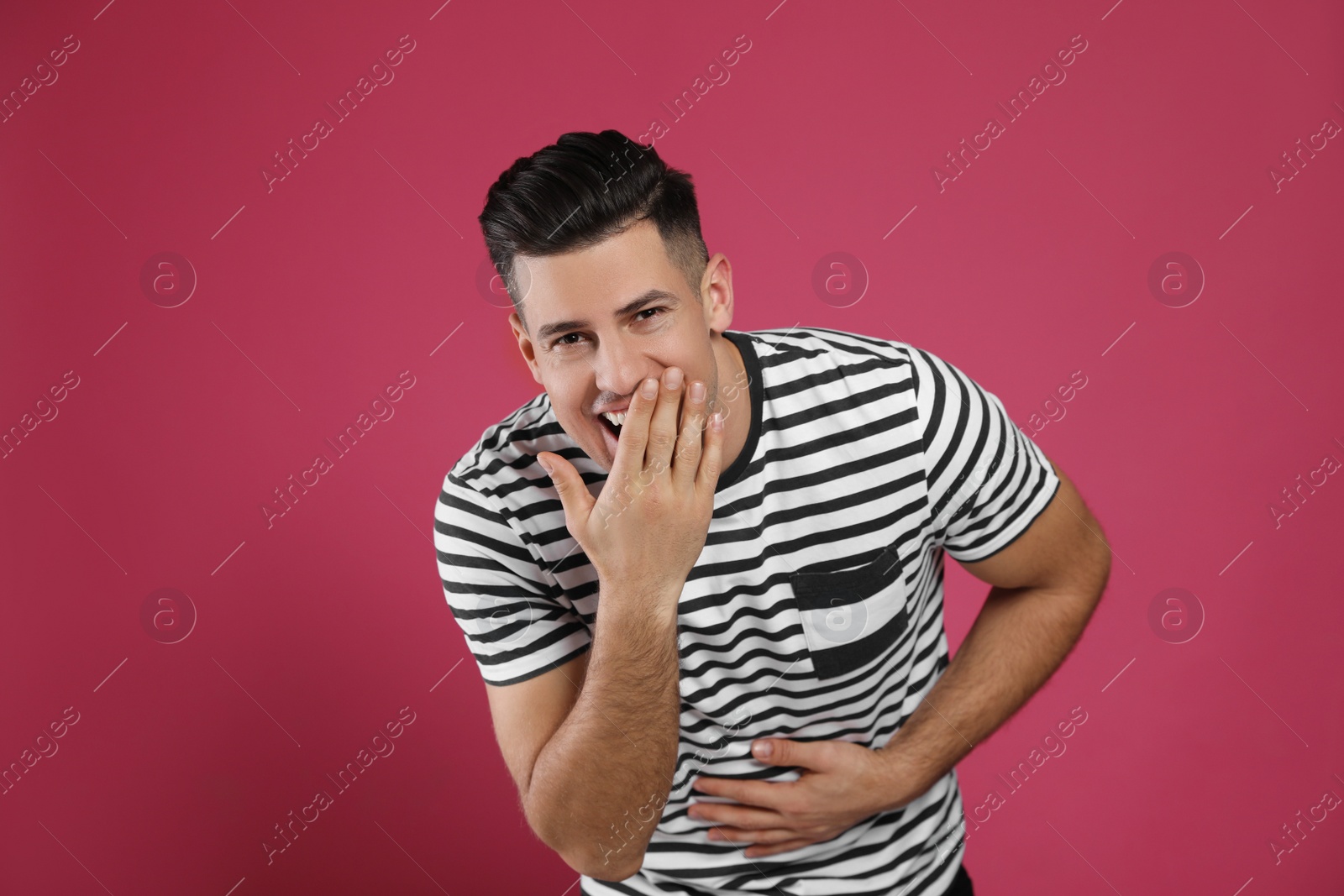 Photo of Handsome man laughing on maroon background. Funny joke