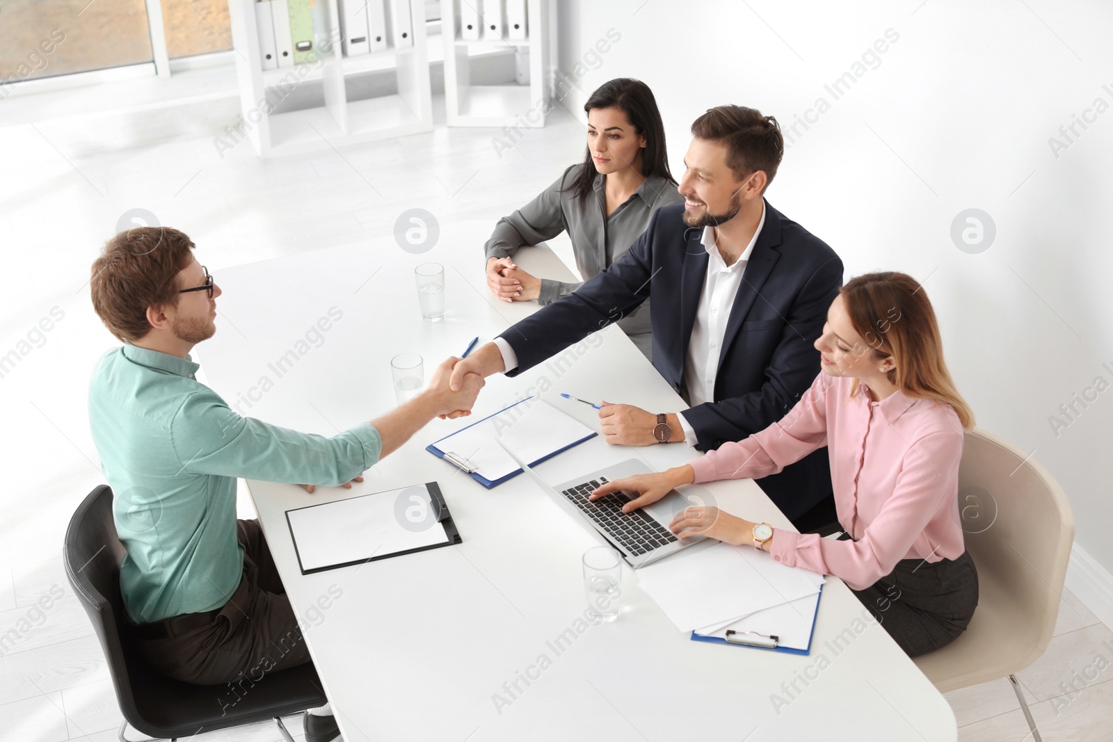 Photo of Human resources manager shaking hands with applicant during job interview in office