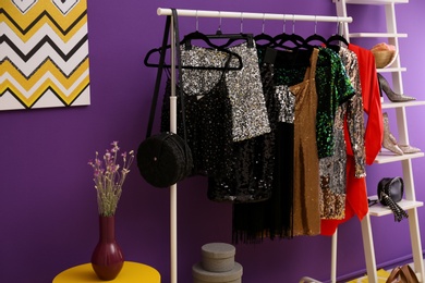 Rack with collection of beautiful festive clothes in stylish room interior