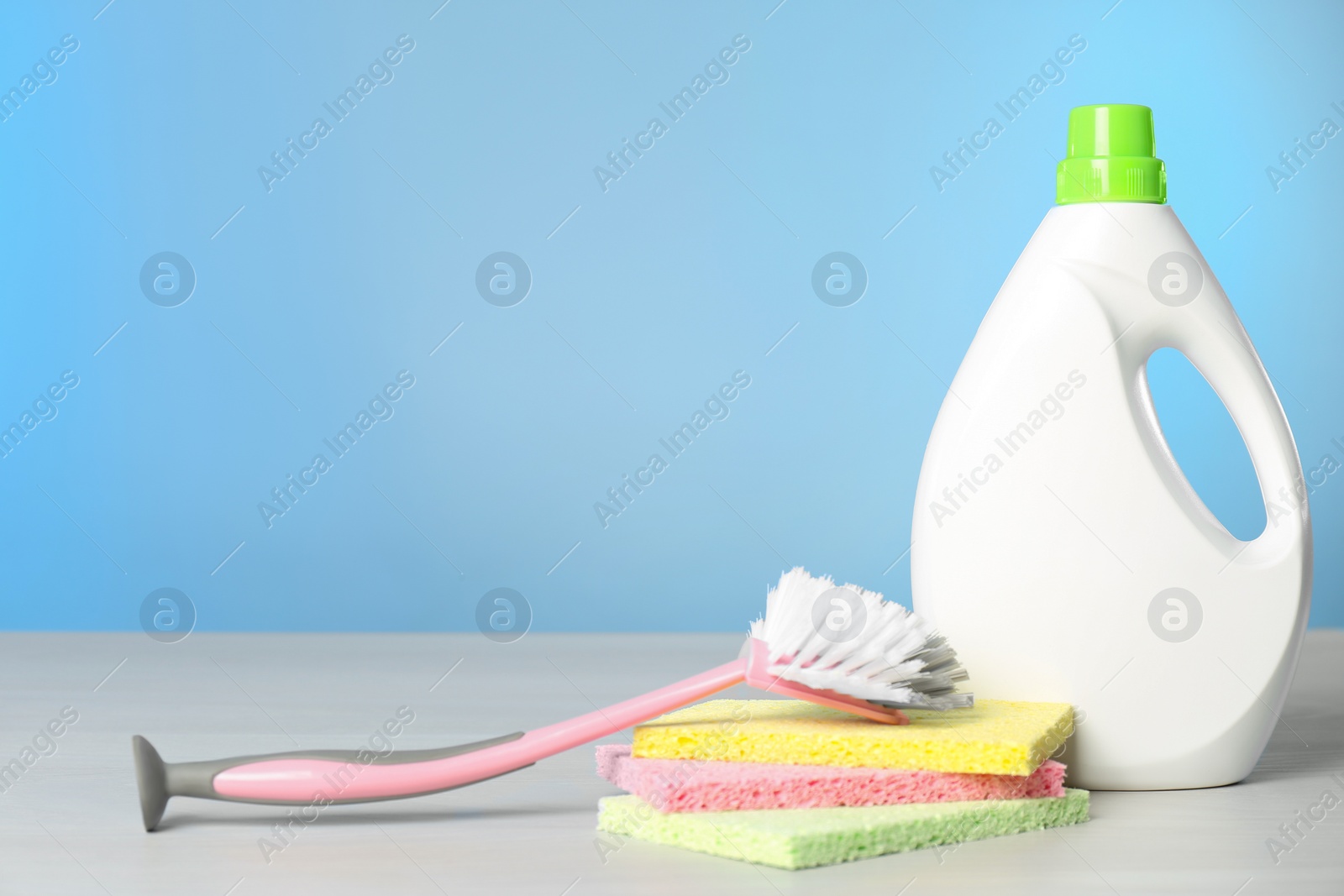 Photo of Bottle of cleaning product and supplies on light table. Space for text