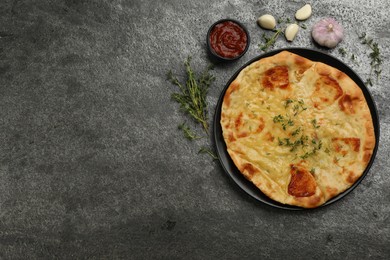 Photo of Delicious khachapuri with cheese, thyme, garlic and sauce on grey table, flat lay. Space for text