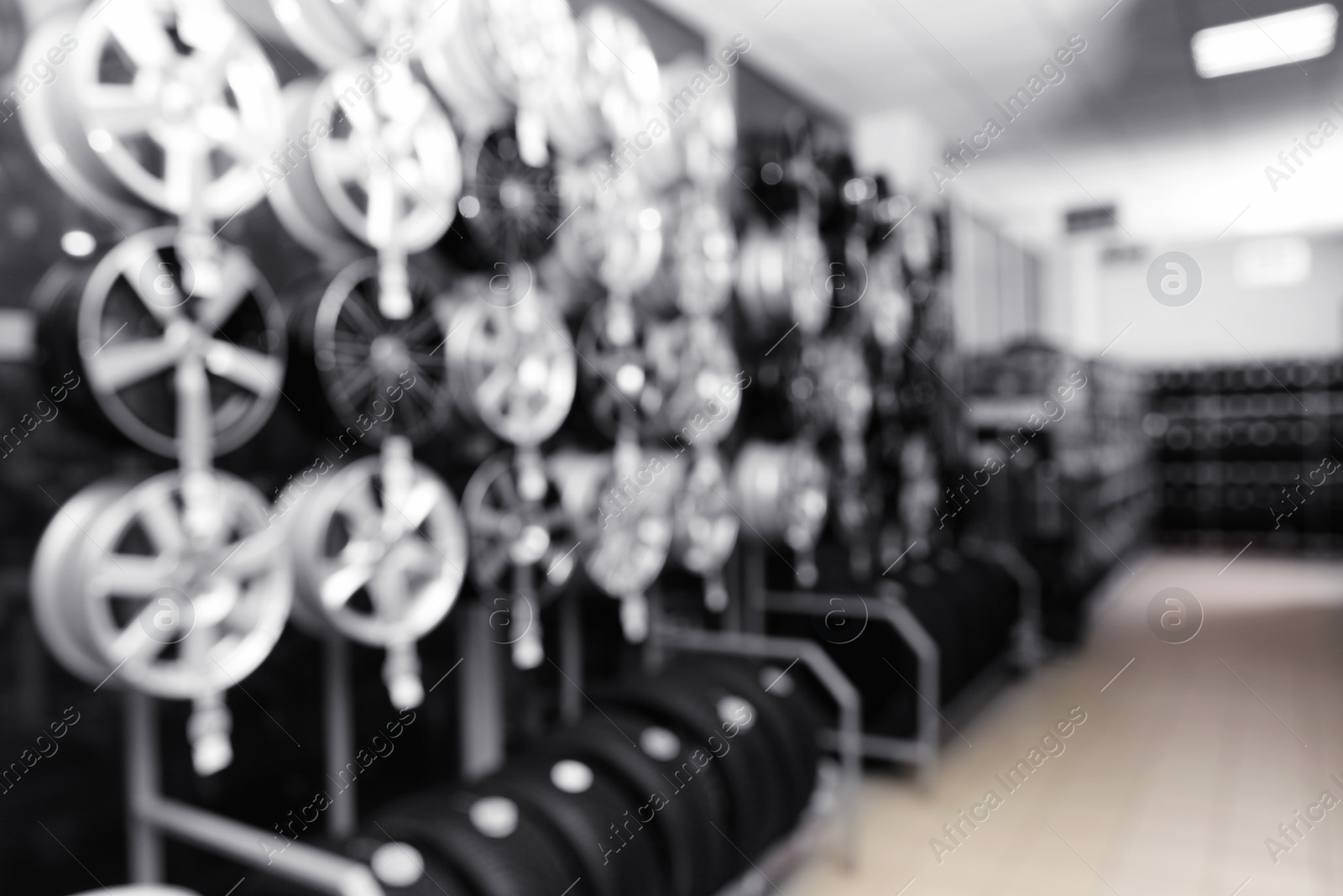 Photo of Blurred view of car tires and alloy wheels on rack in auto store