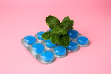 Photo of Blister with cough drops and mint leaves on pink background